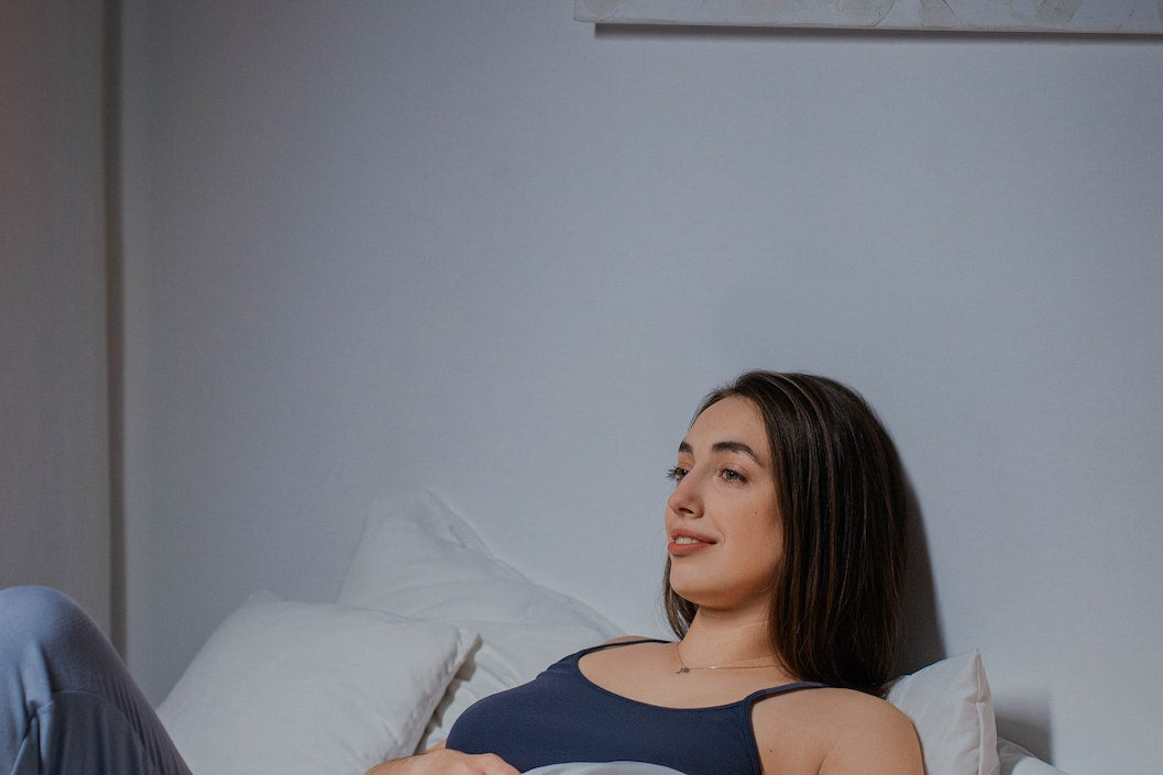 woman laying on bed with pregnancy pillow