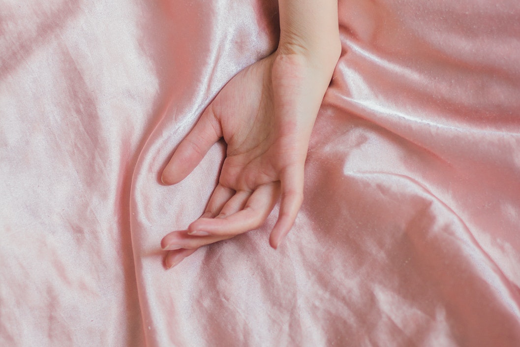 woman hand on crumpled bed sheet